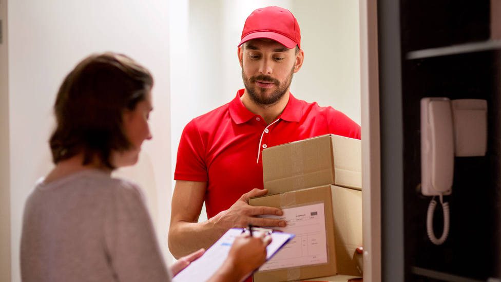 Persona recibiendo paquete en puerta casa